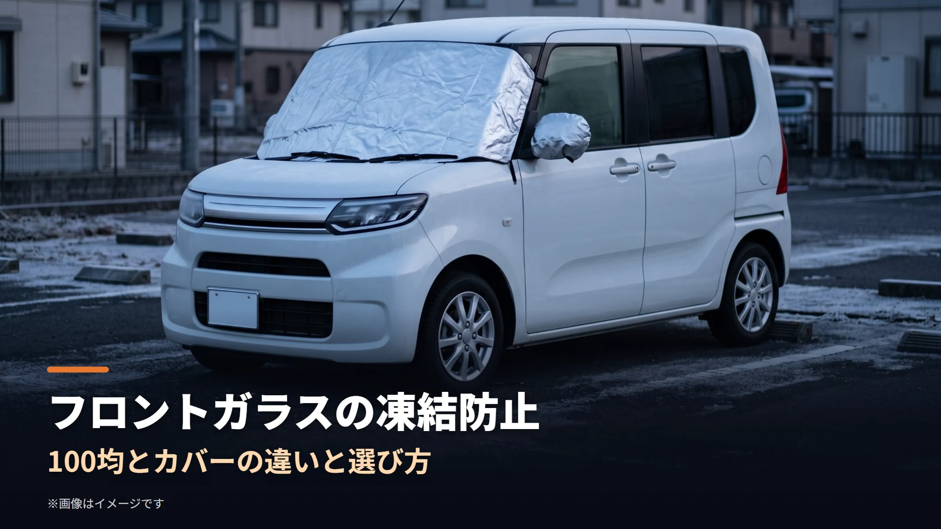 冬の早朝、霜が降りた駐車場で、フロントガラスとドアミラーに銀色の凍結防止カバーを被せた白い小型トールワゴンのイメージ画像（フロントガラスの凍結防止の記事用）